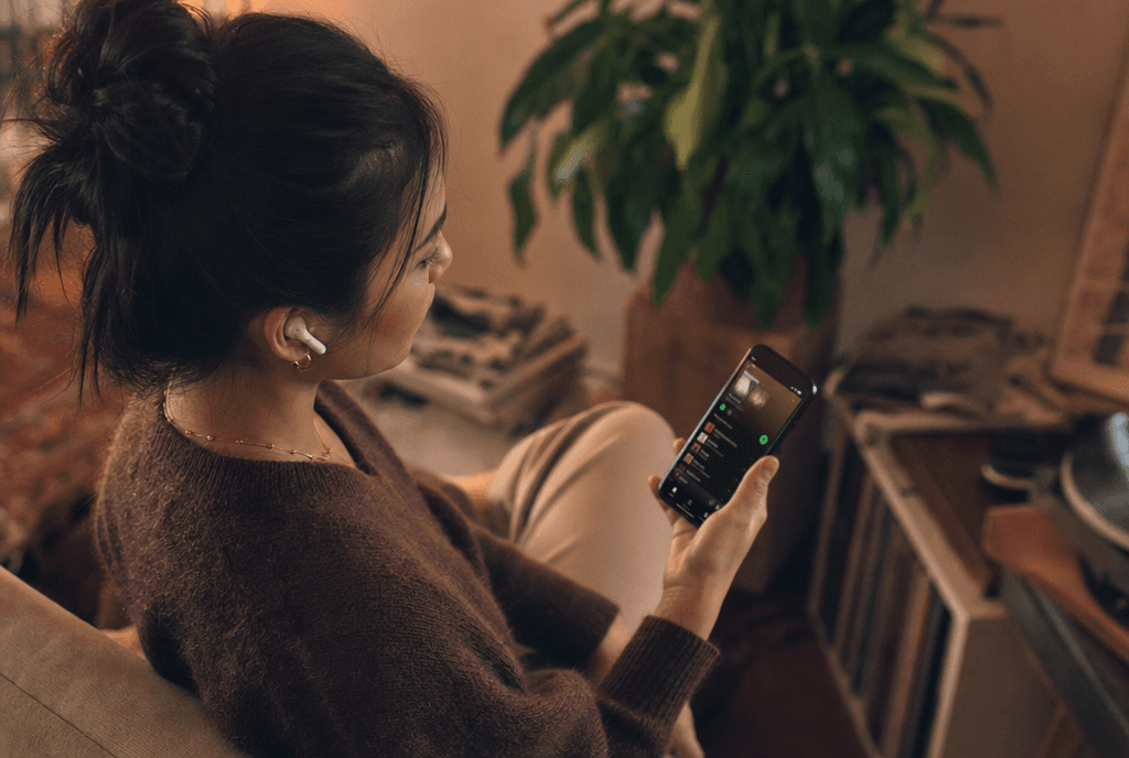 Person with earbuds listening to music on their smartphone