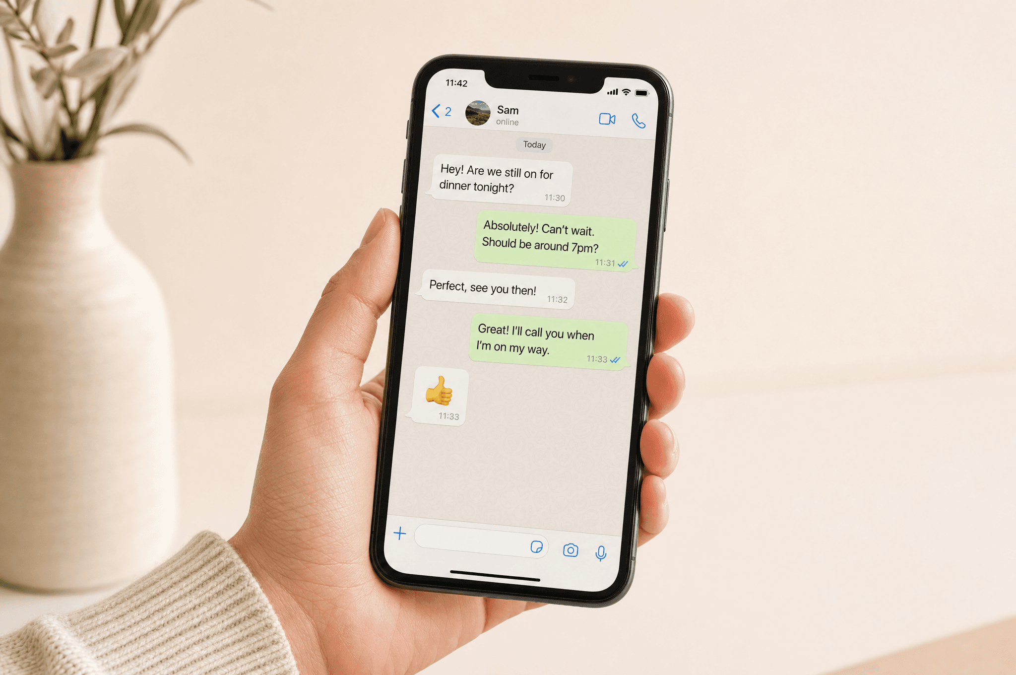 Hand holding smartphone showing a WhatsApp conversation